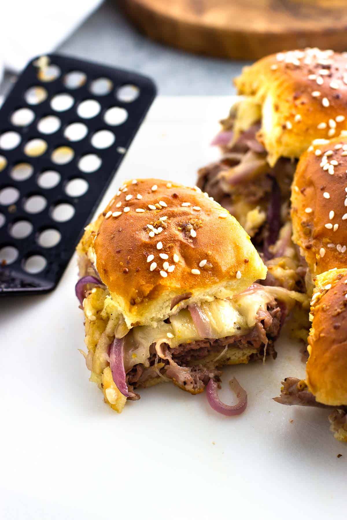 Roast beef sliders on a cutting board with a spatula.