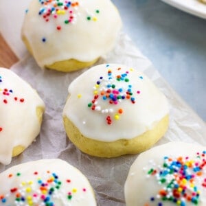 Glazed anginetti cookies on a crinkled sheet of parchment paper.