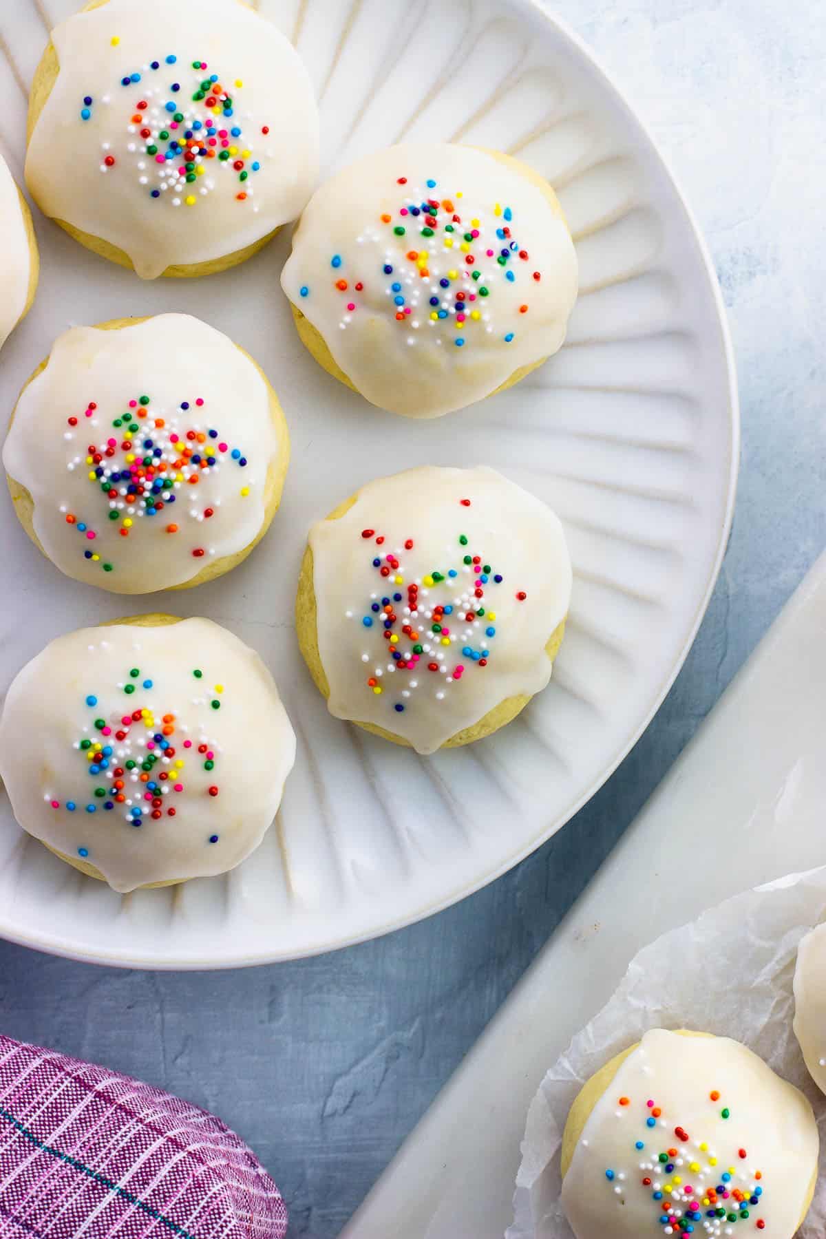 A plate of anginetti cookies topped with lemon glaze and nonpareils.