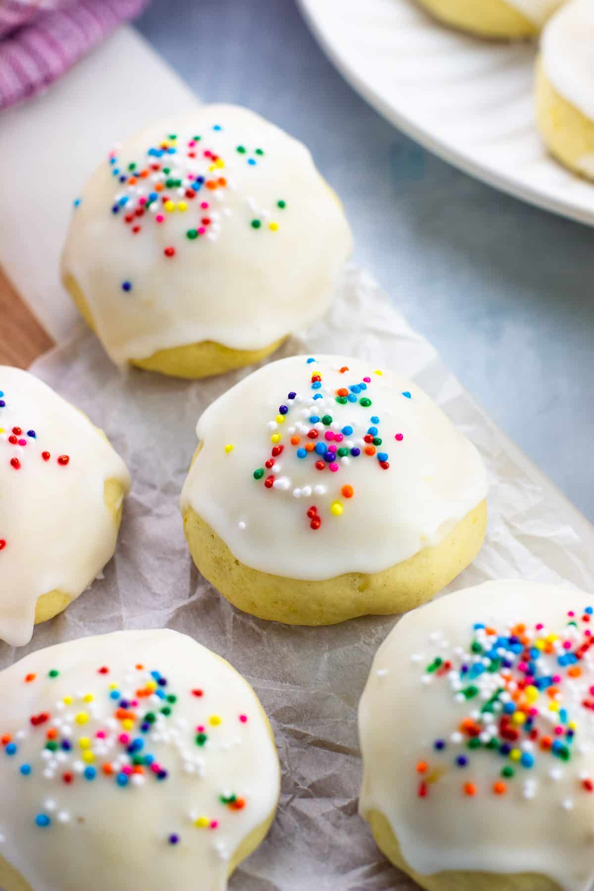 Glazed anginetti cookies on a crinkled sheet of parchment paper.