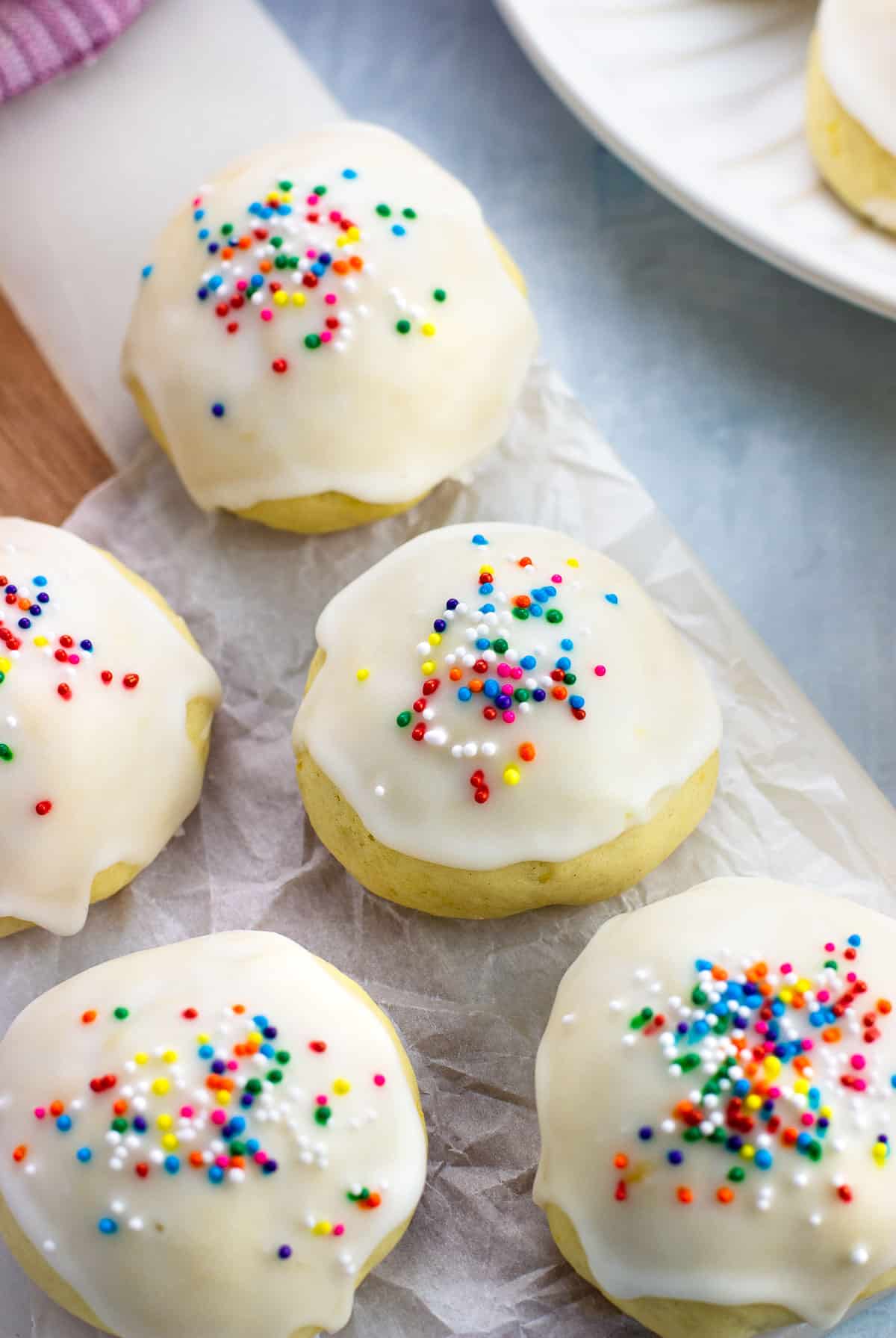 Glazed anginetti cookies on a crinkled sheet of parchment paper.