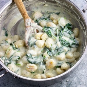 Gnocchi and spinach in a creamy Gorgonzola sauce in a stainless steel saucepan.