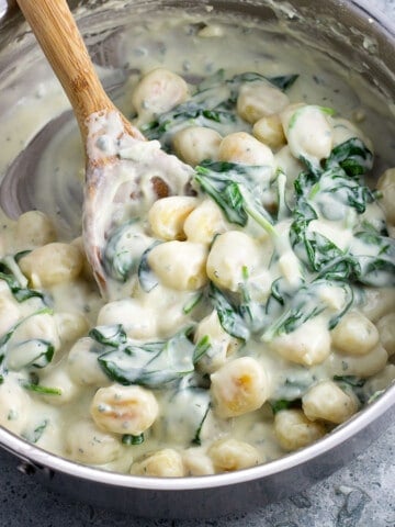 Gnocchi and spinach in a creamy Gorgonzola sauce in a stainless steel saucepan.