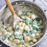 A pan of creamy Gorgonzola gnocchi with a wooden serving spoon.