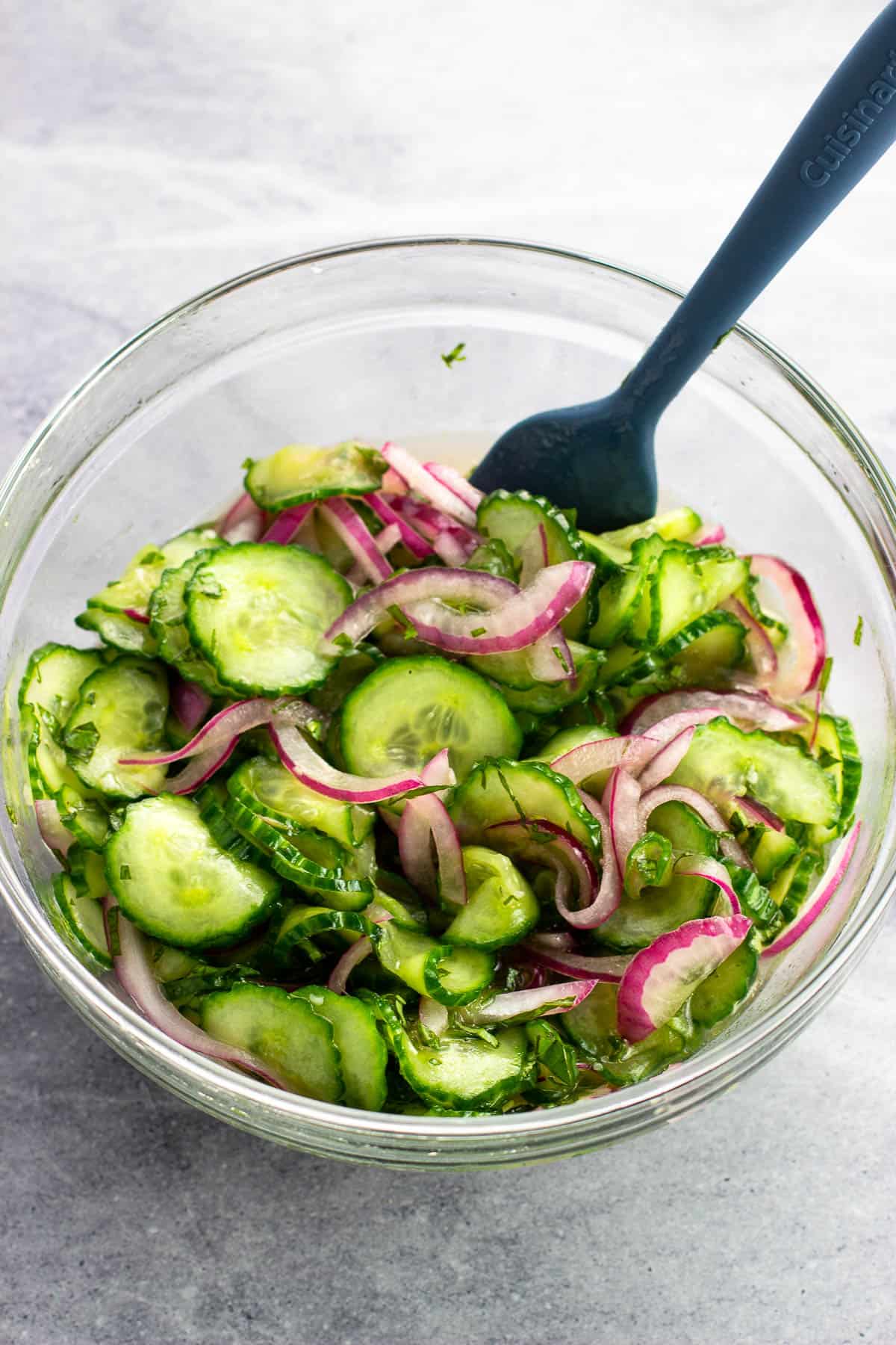 Marinated cucumber and onion salad in a glass bowl.