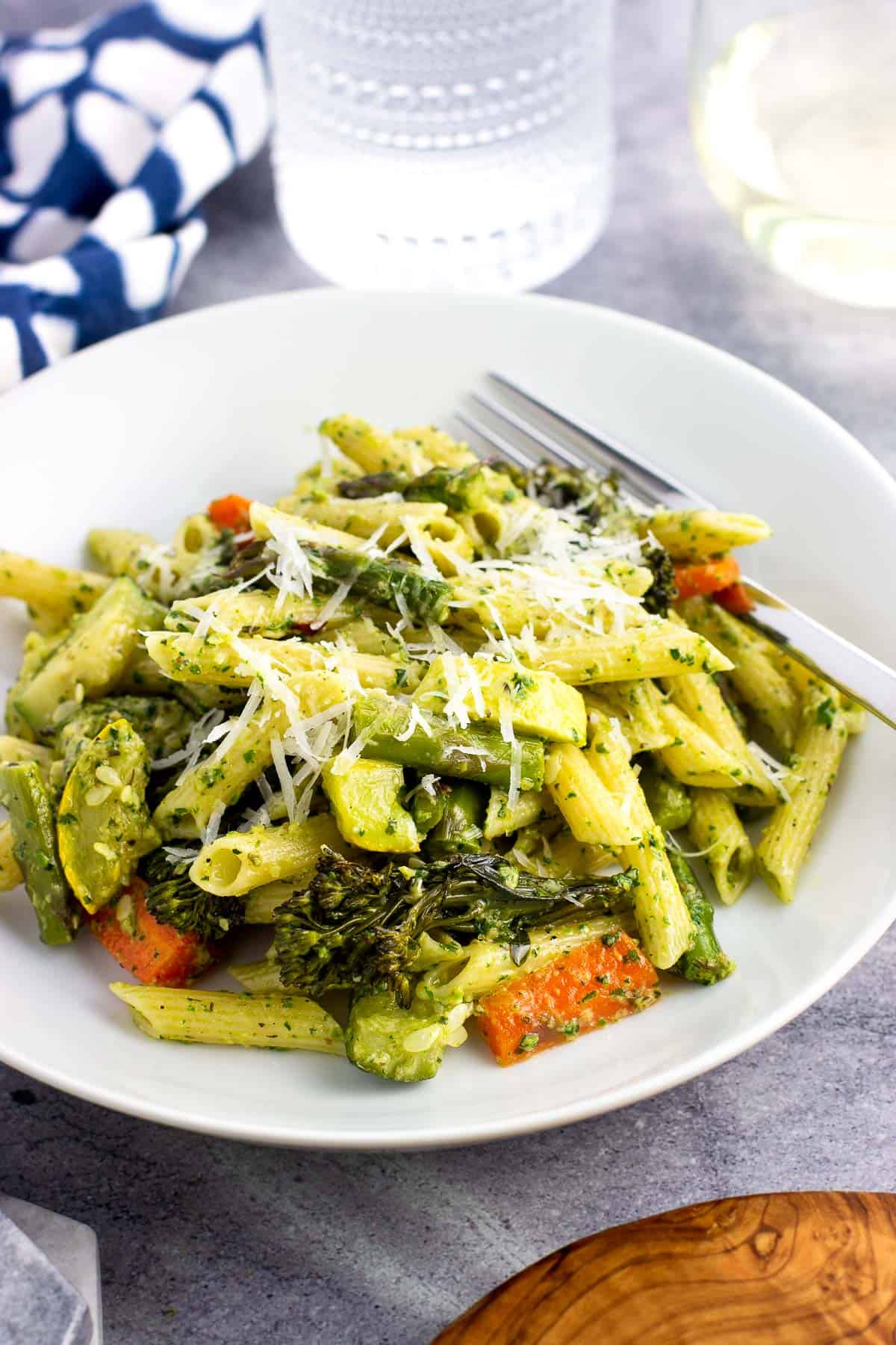 A shallow bowl of pesto pasta primavera with a fork.