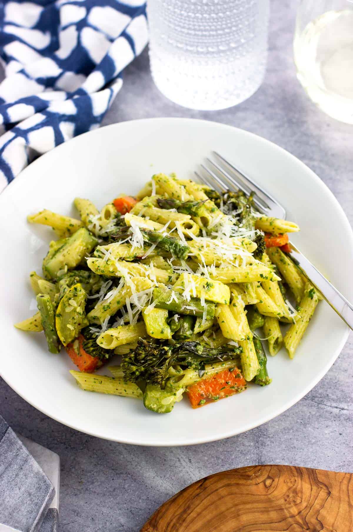 A serving of pesto pasta primavera topped with grated Pecorino.