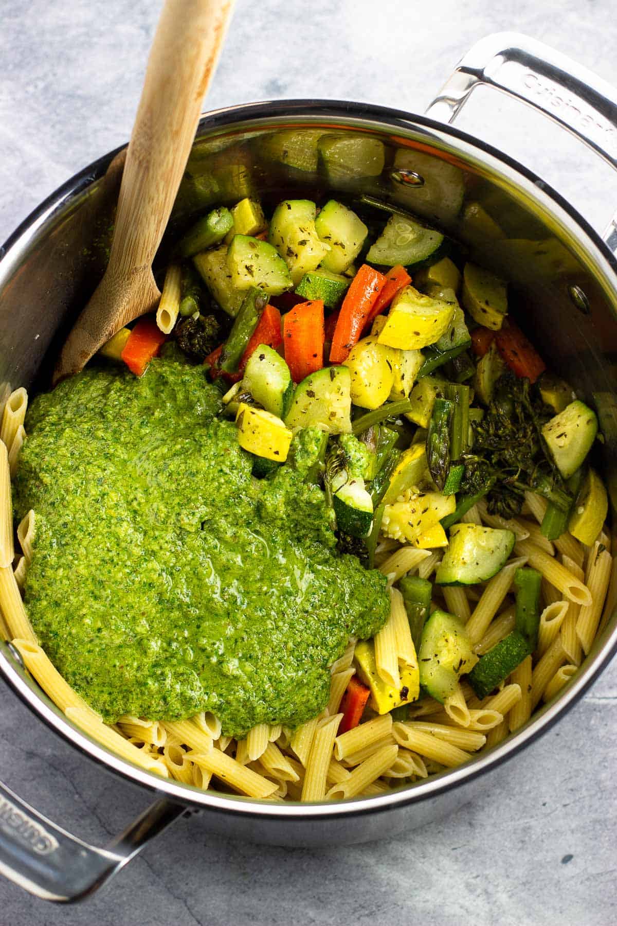 Cooked pasta and vegetables in a pot with the pesto sauce poured in.