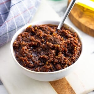 Blended pesto rosso sauce in a bowl with a spoon.