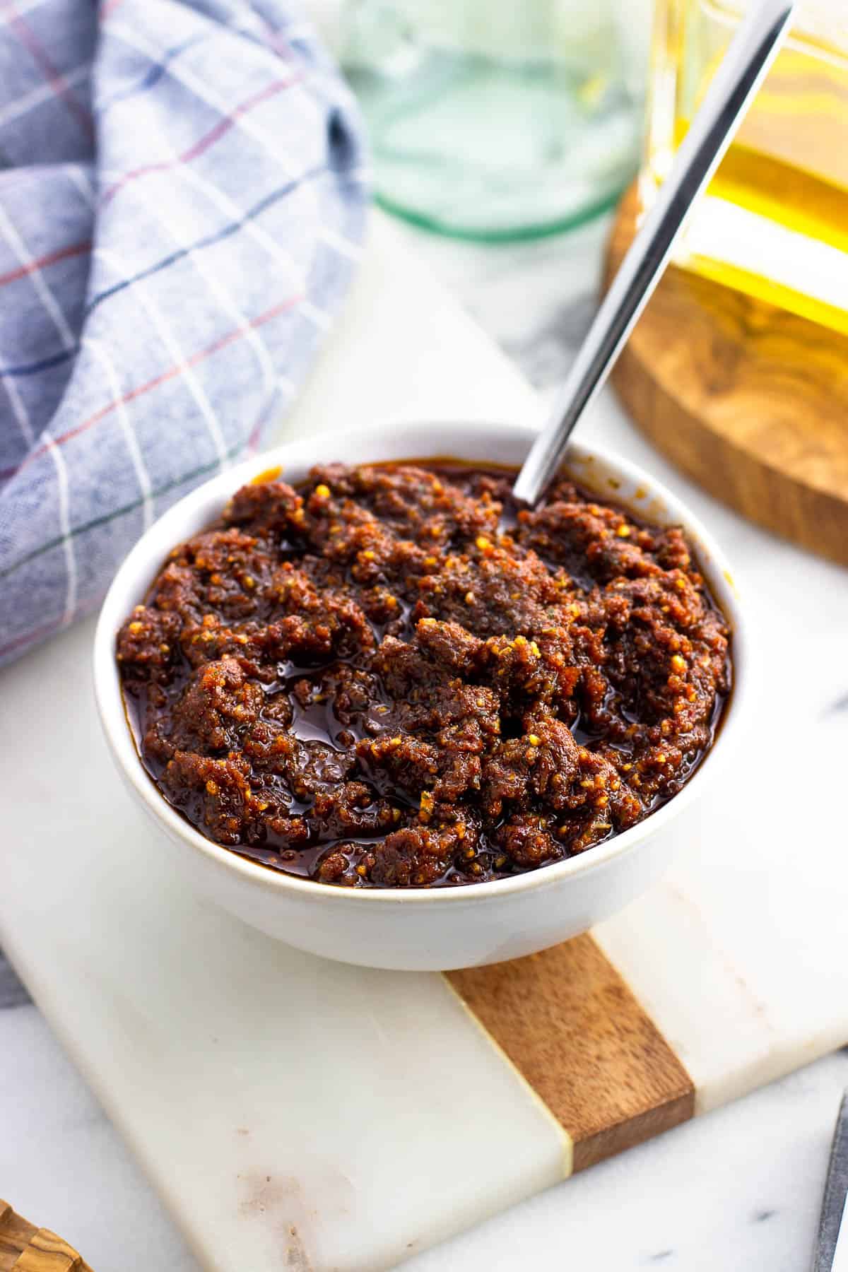 Blended pesto rosso sauce in a bowl with a spoon.