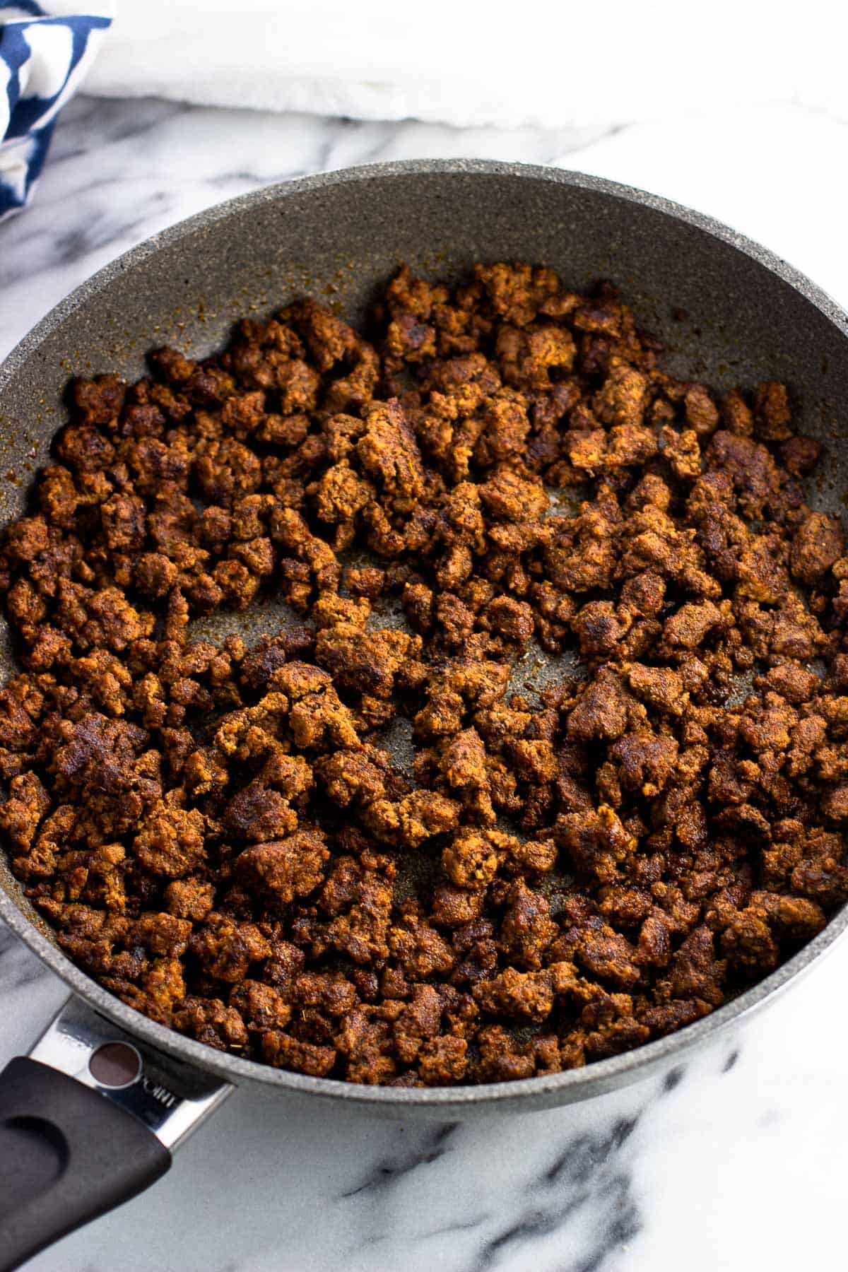 Cooked and seasoned ground beef crumbles in a skillet.