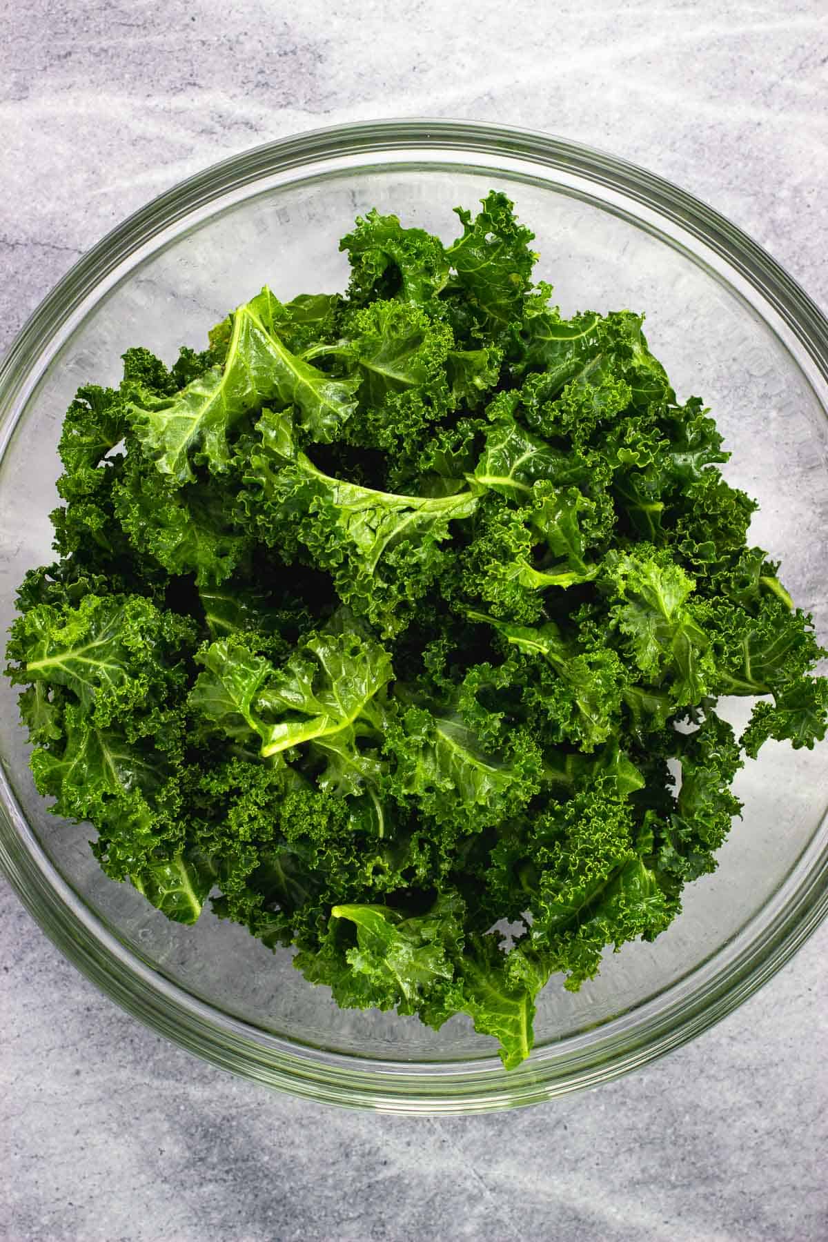 A bowl of olive oil massaged kale leaves.