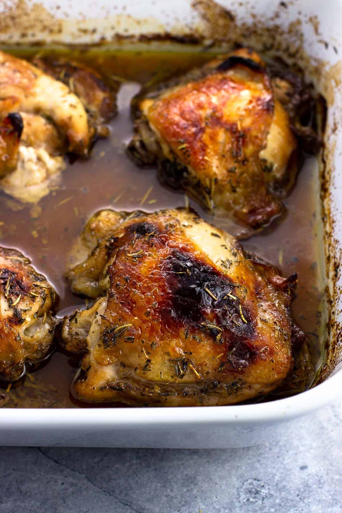 Bone-in marinated chicken thighs baked in a dish.