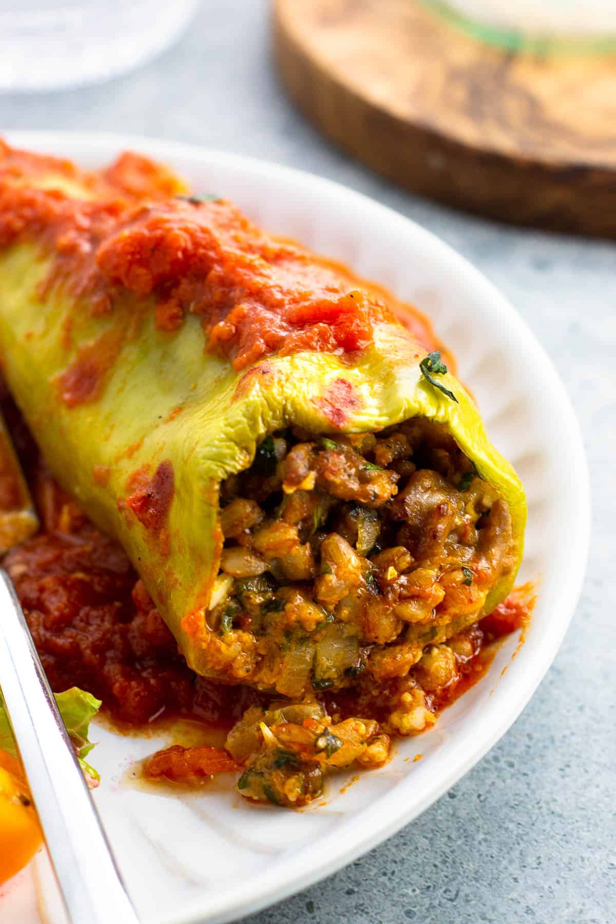 A farro and sausage stuffed cubanelle pepper on a plate with a side salad.