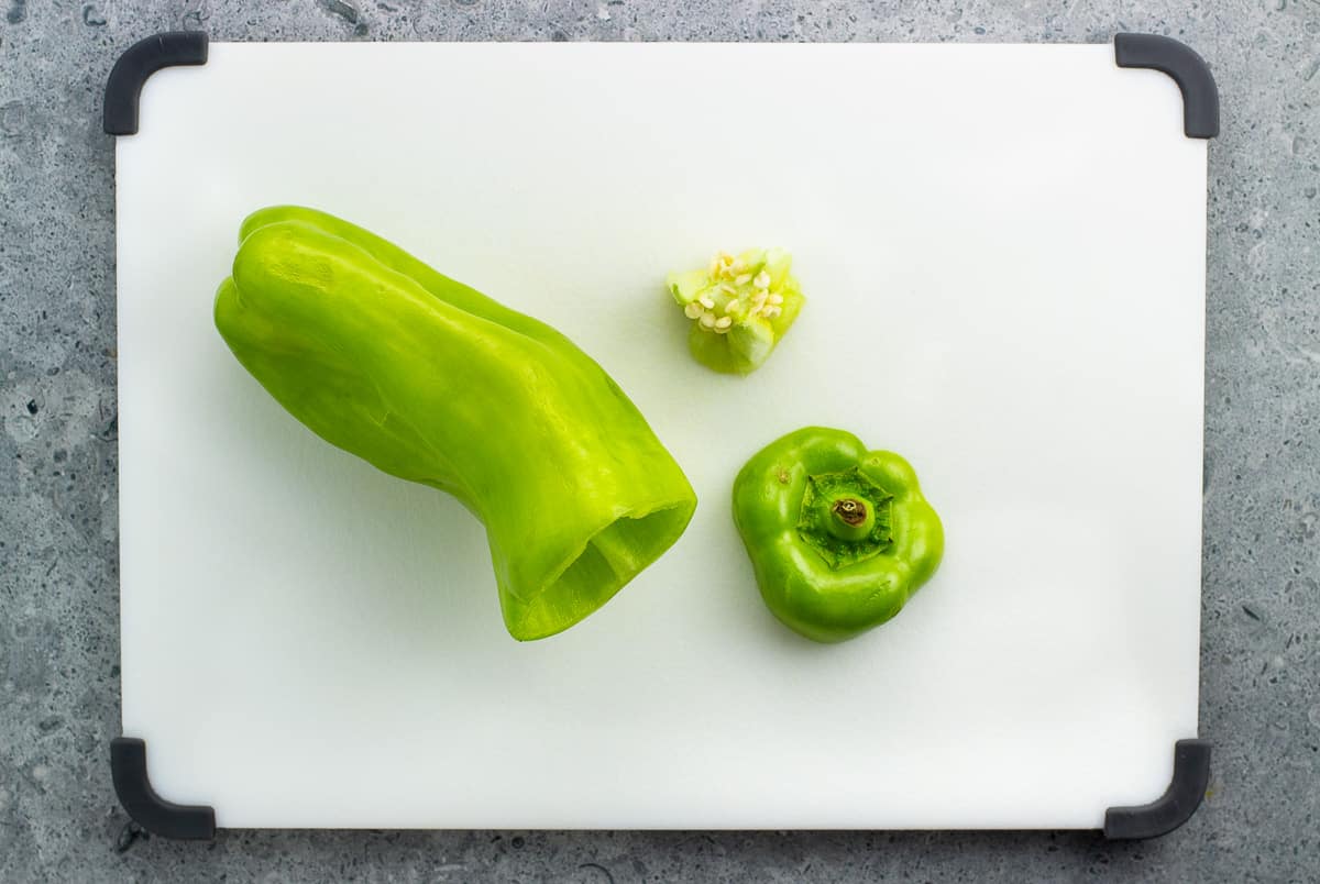 A cubanelle pepper on a cutting board with the top sliced off and seeds removed.