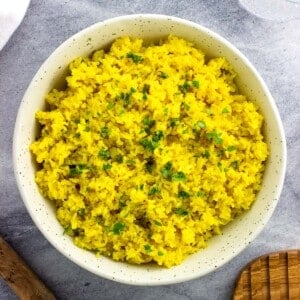 A ceramic bowl of rice garnished with chopped cilantro.