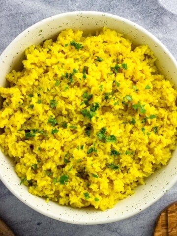 A ceramic bowl of rice garnished with chopped cilantro.