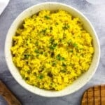 A ceramic bowl of rice garnished with chopped cilantro.