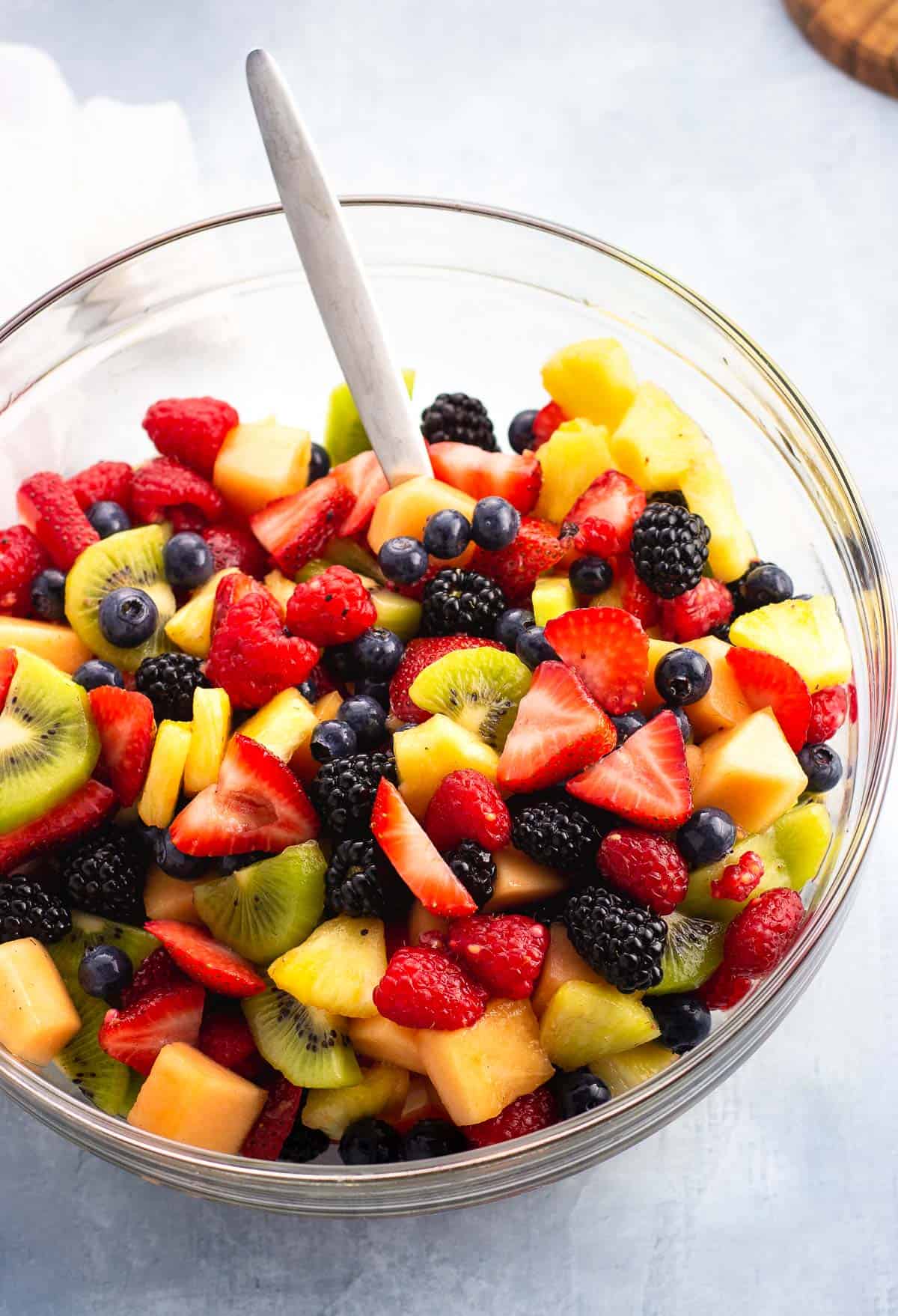 Stirred together anise fruit salad in a large glass bowl.