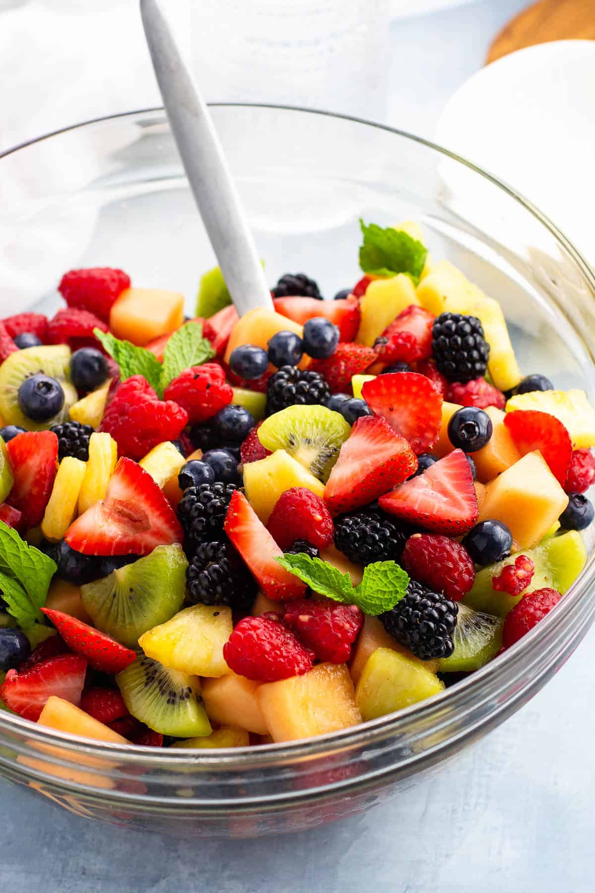 Fruit salad tossed in anise cinnamon syrup in a serving bowl garnished with mint leaves.