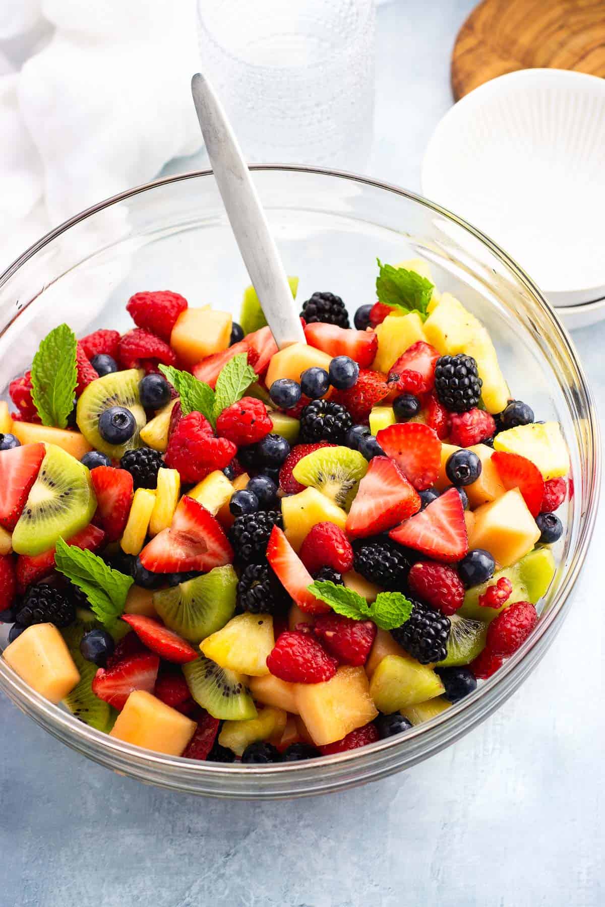 Anise fruit salad in a glass serving bowl with a spoon.