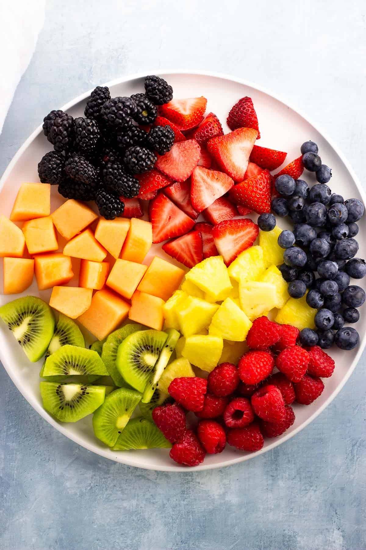 Chopped fruit and berries on a large plate.