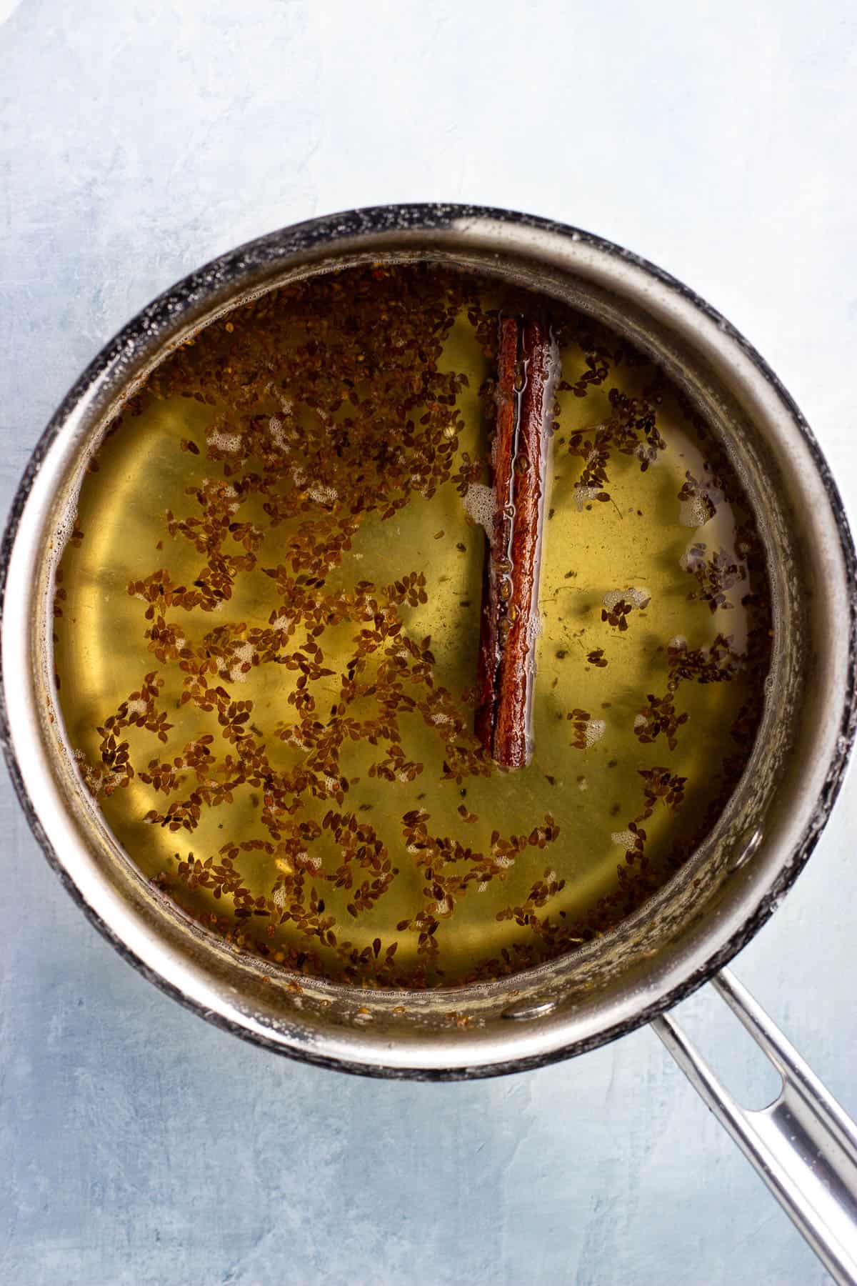 Simple syrup in a pan infused with anise seeds and a cinnamon stick.