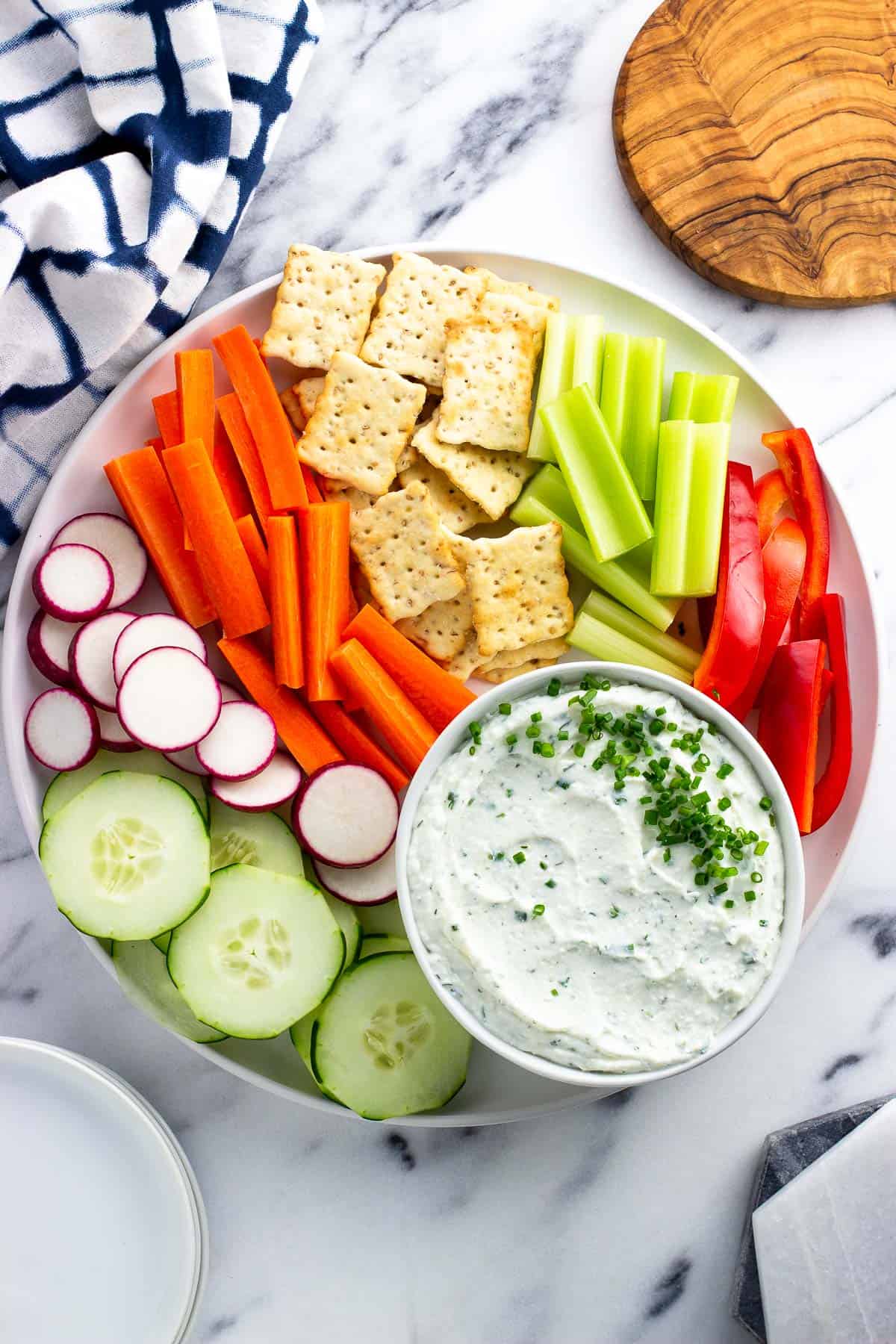 Cottage cheese dip on a platter with vegetables and crackers.