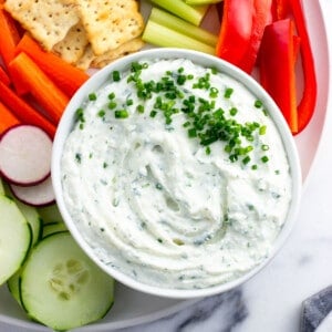 Cottage cheese dip on a platter with vegetables and crackers.