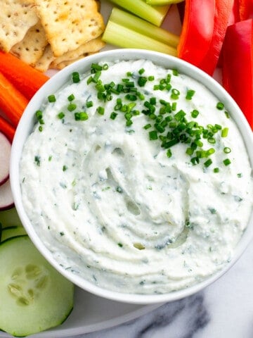 Cottage cheese dip on a platter with vegetables and crackers.