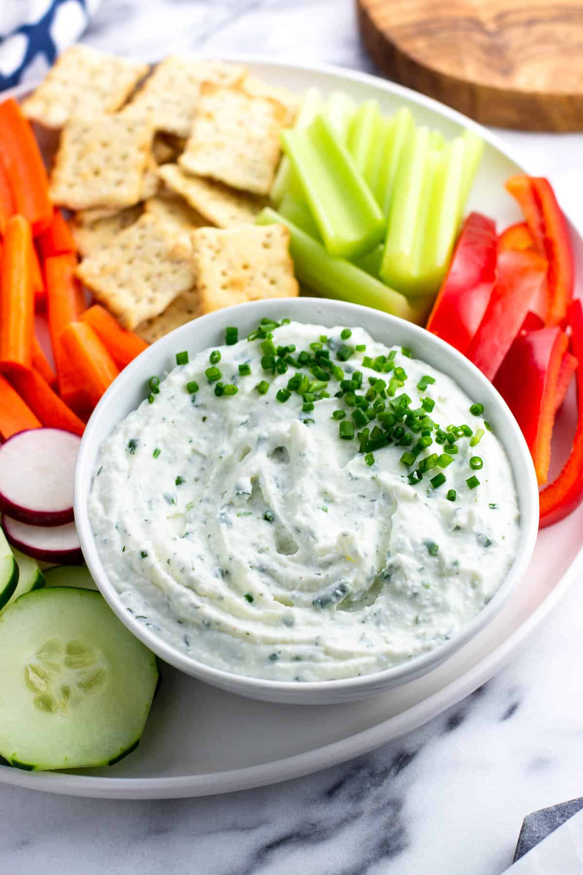 Creamy herbed cottage cheese dip on a platter with vegetables and crackers.