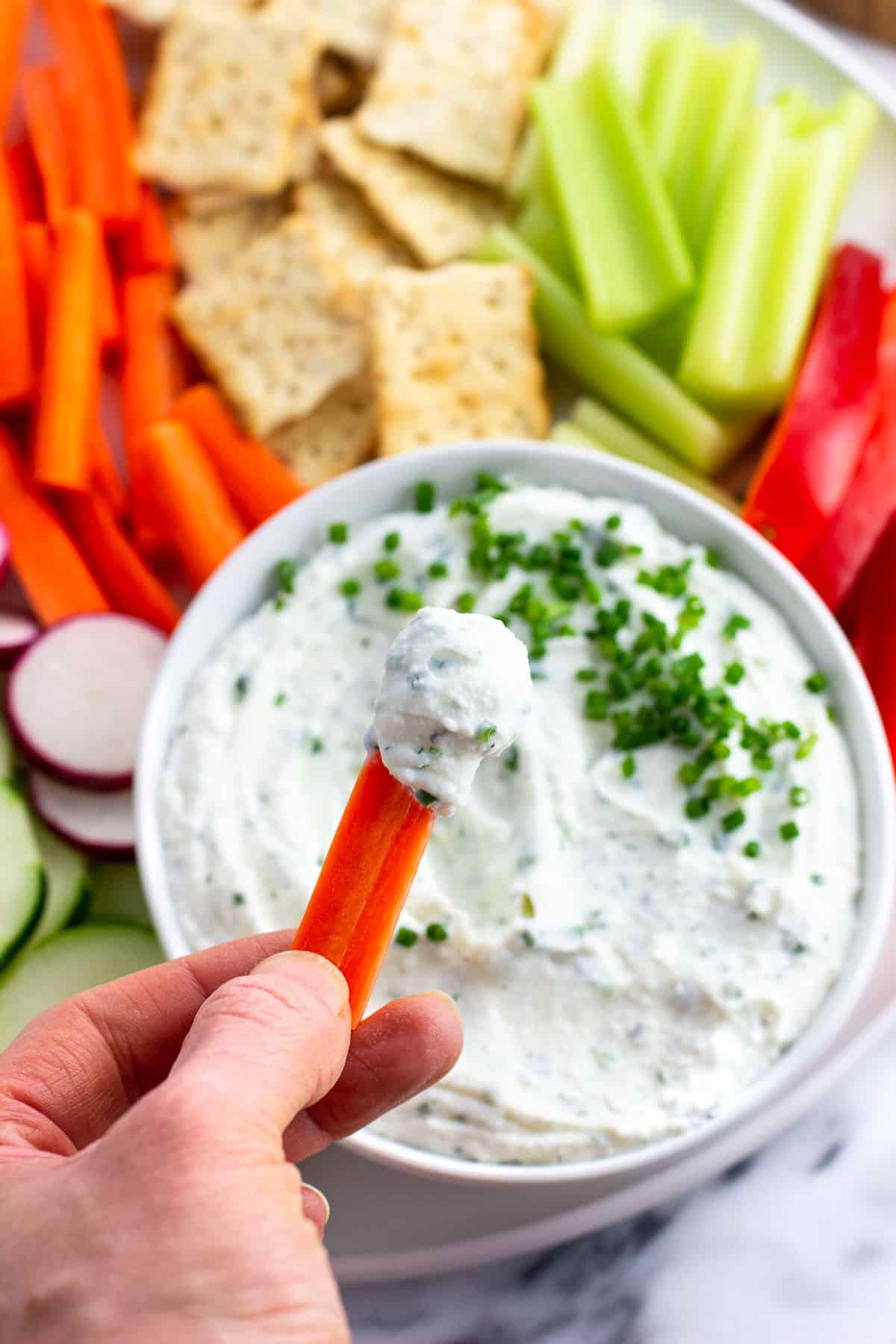 A carrot stick dipped into cottage cheese dip.