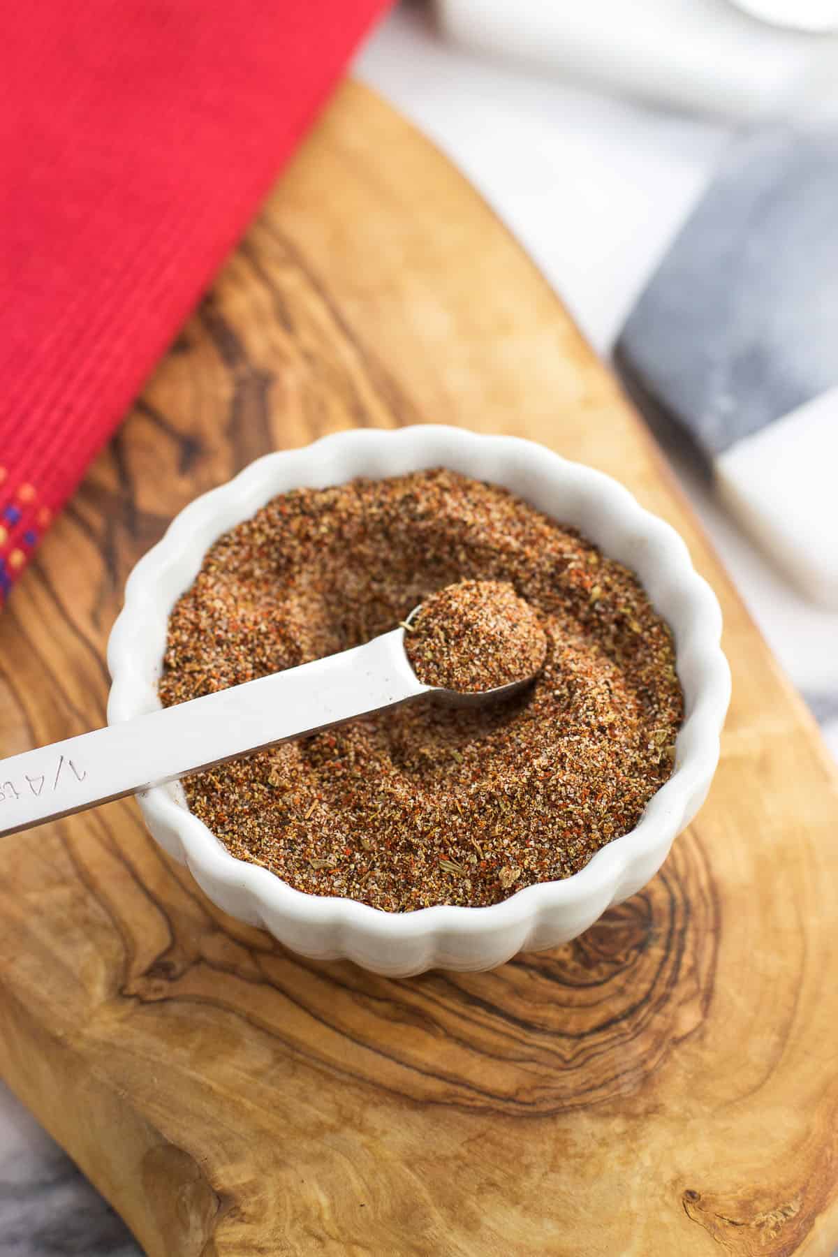 A small measuring spoon dipped into a bowl of taco seasoning.