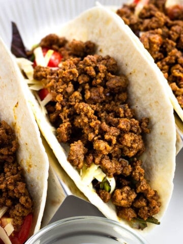 Three ground beef tacos in a holder.