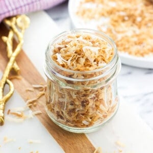 A glass jar filled with toasted coconut flakes.