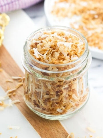 A glass jar filled with toasted coconut flakes.