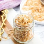 A glass jar filled with toasted coconut flakes.