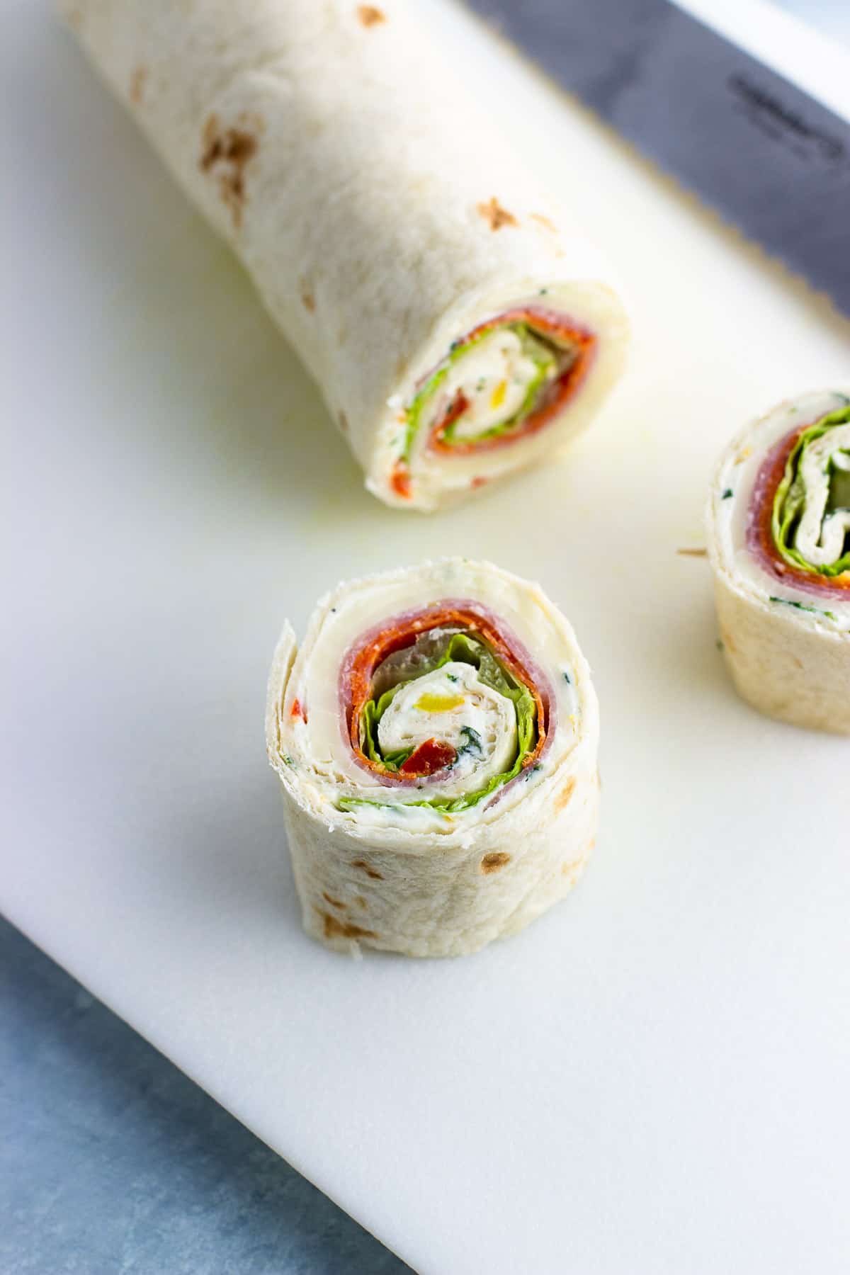 A rolled-up tortilla being sliced into pinwheels.