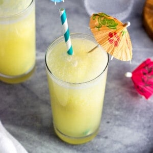 A pina colada mocktail in a glass with a straw and paper drink umbrella.