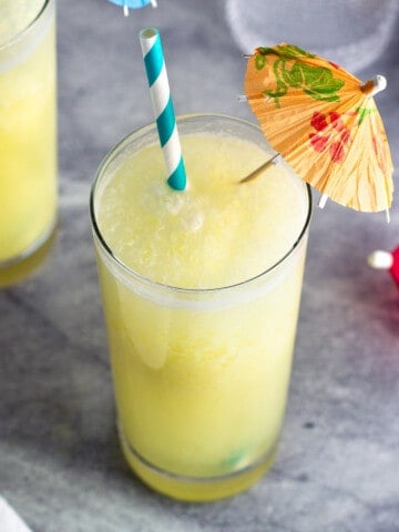 A pina colada mocktail in a glass with a straw and paper drink umbrella.