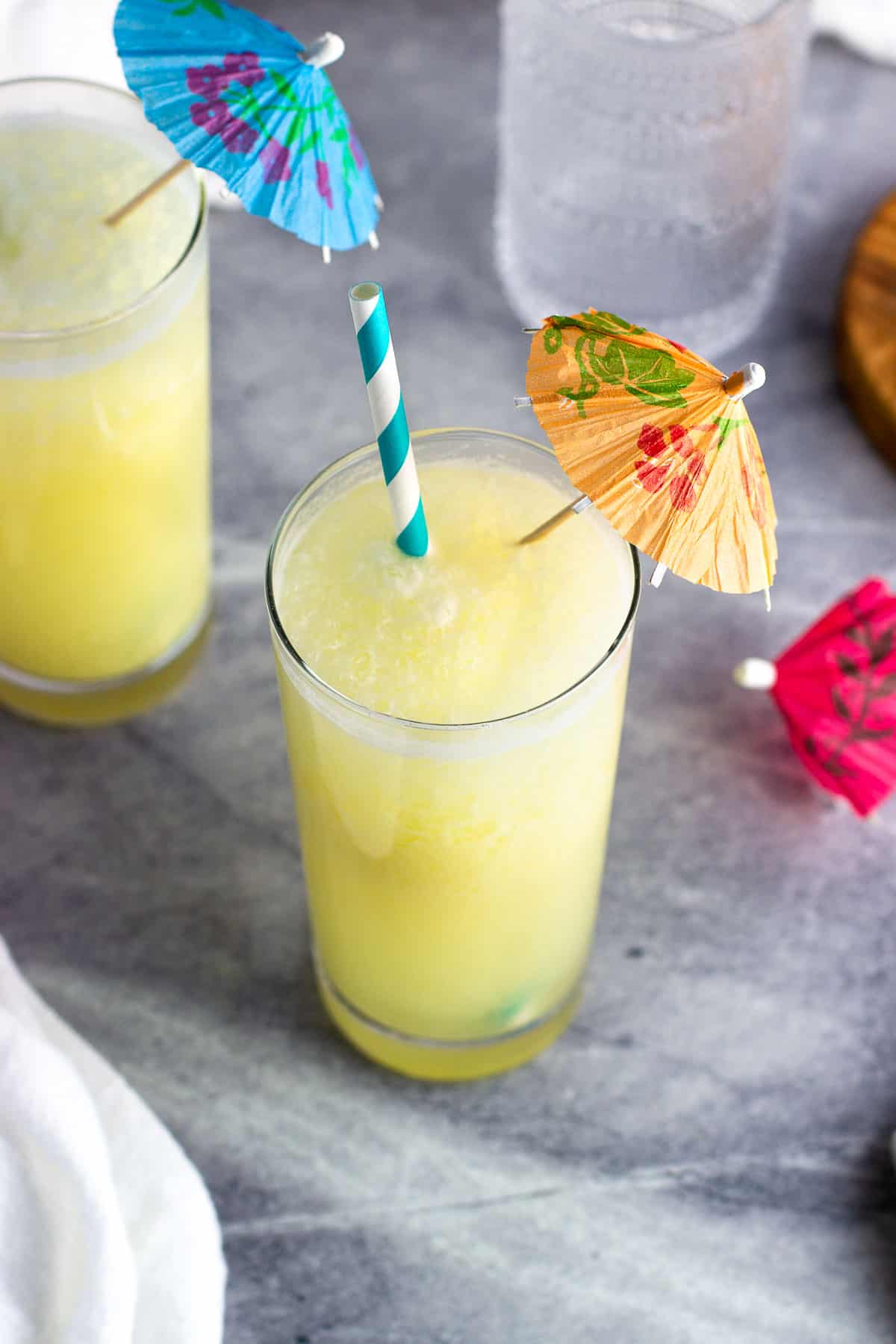 A pina colada mocktail in a glass with a straw and paper drink umbrella.
