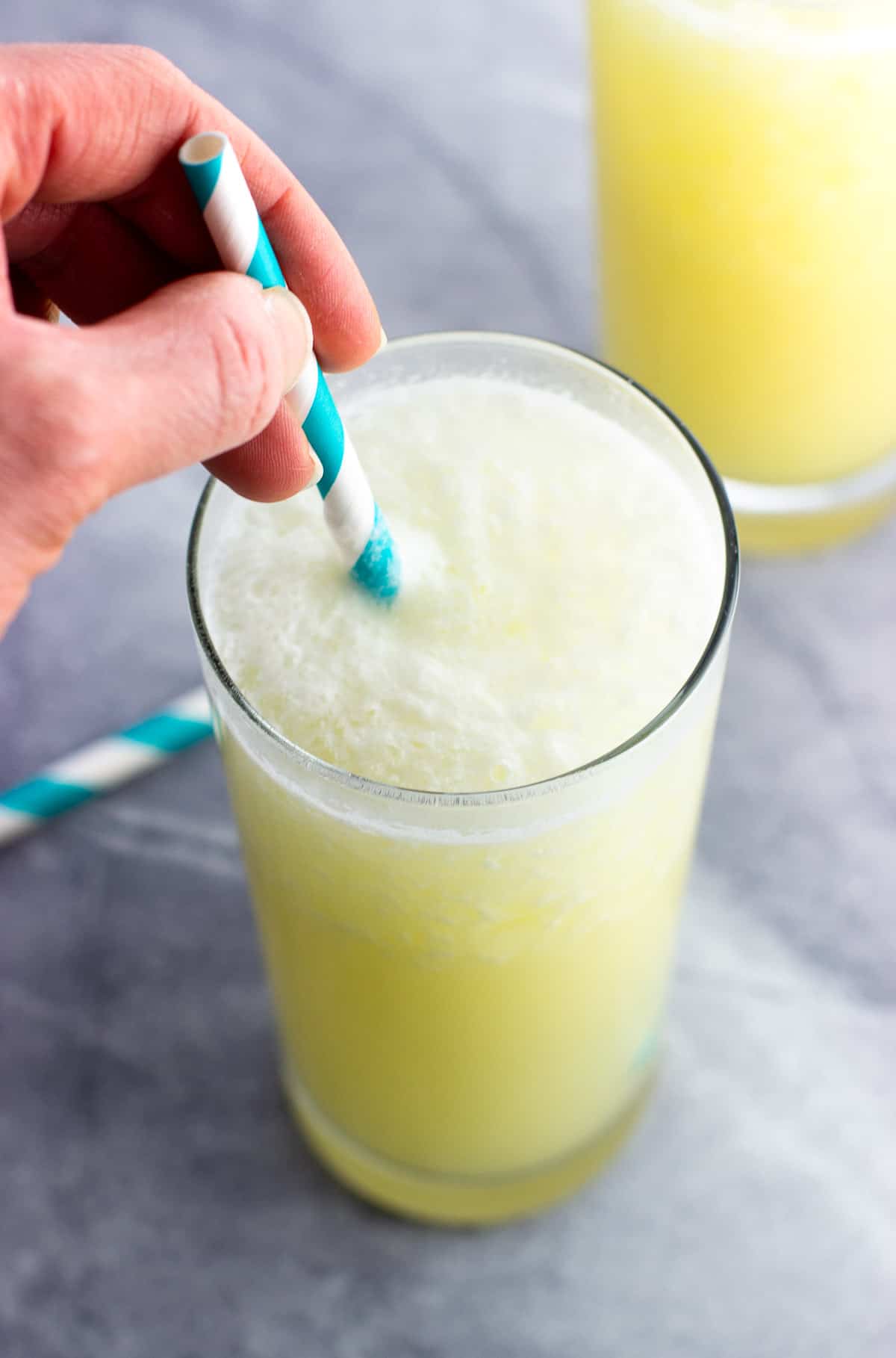 Stirring sparkling water into a virgin pina colada with a straw.
