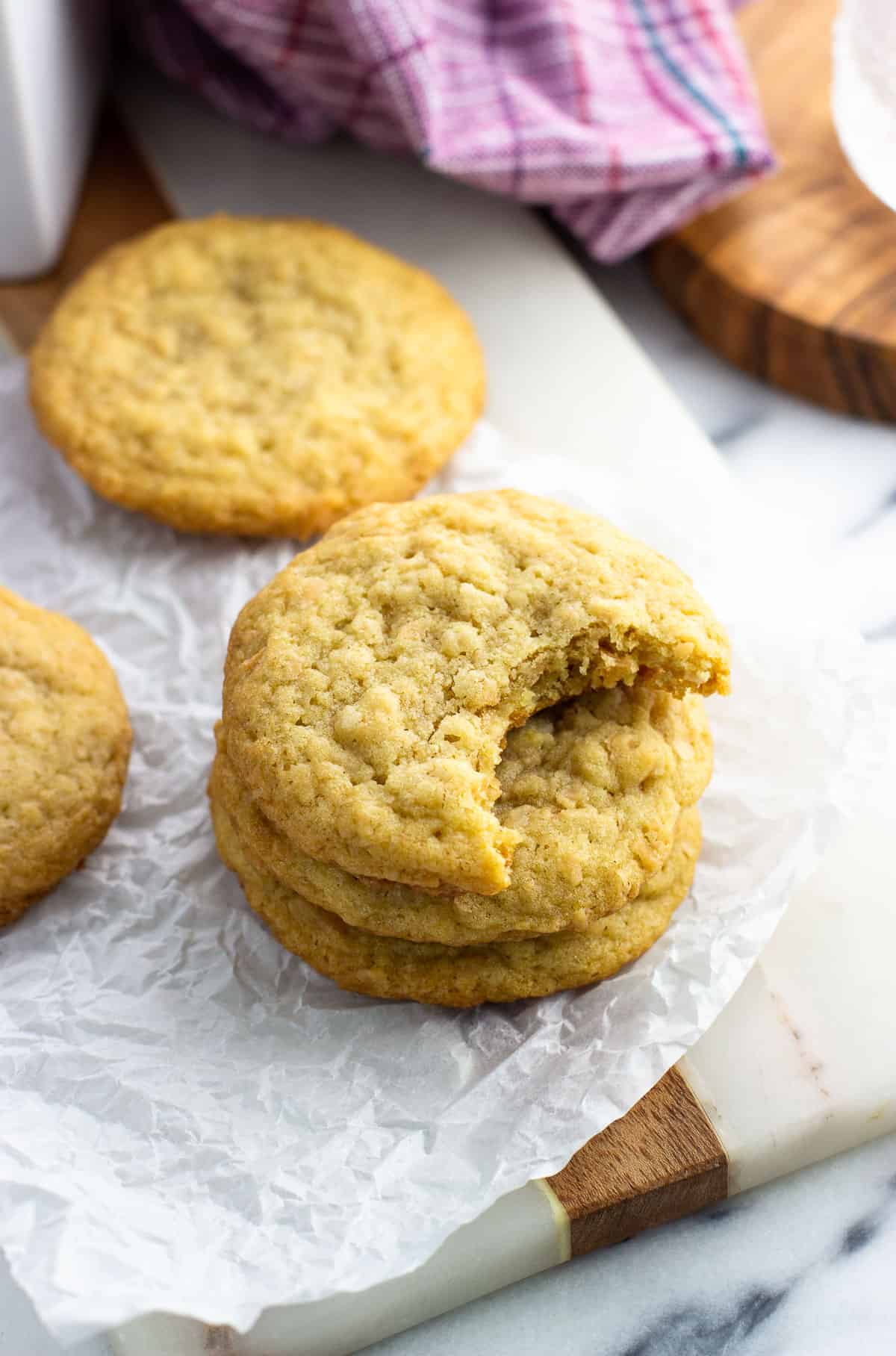 A stack of three coconut cookies on a piece of crinkled parchment paper.