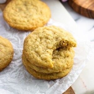 A stack of three coconut cookies on a piece of crinkled parchment paper.