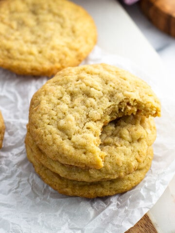 A stack of three coconut cookies on a piece of crinkled parchment paper.