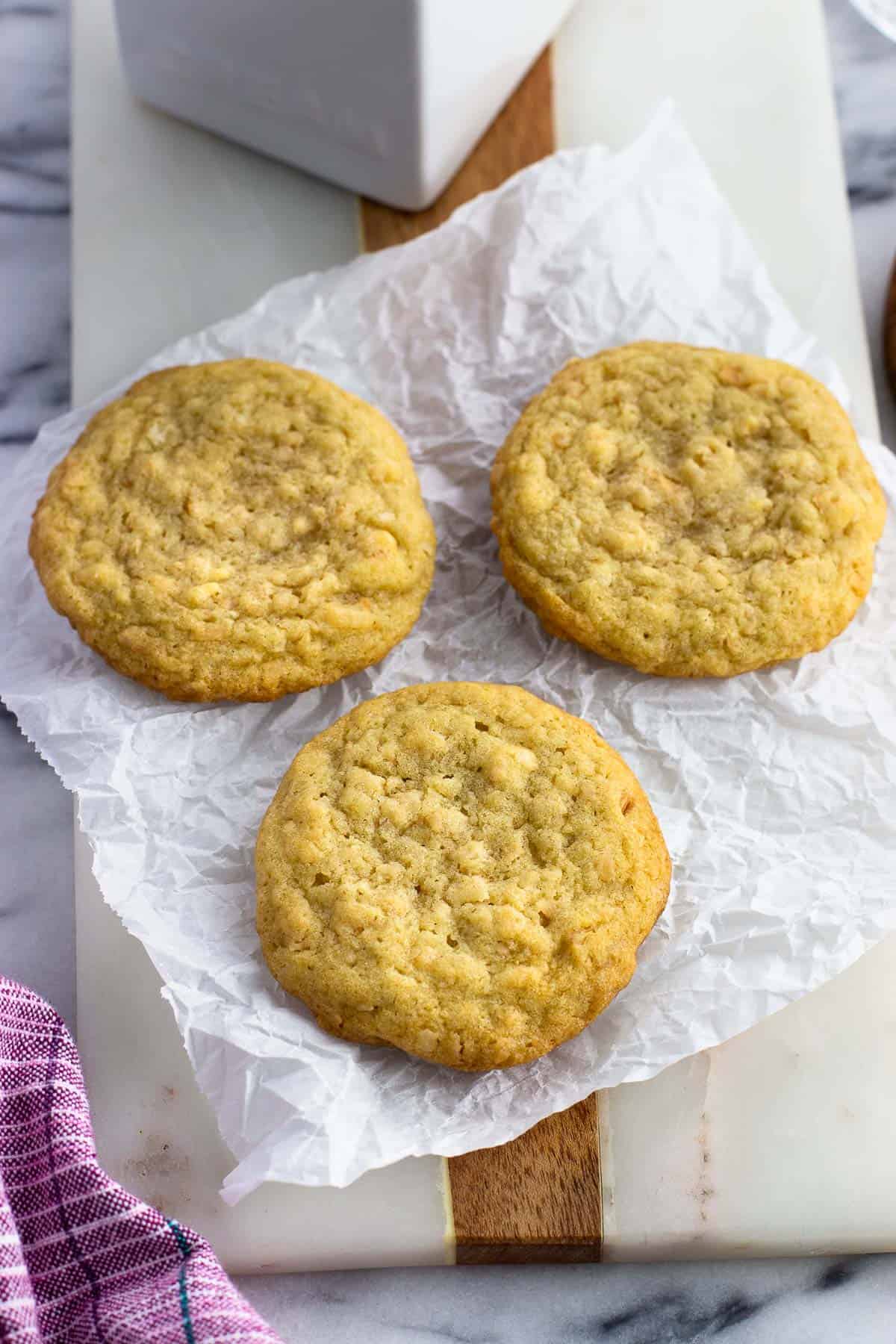 Three toasted coconut cookies on a sheet of parchment.