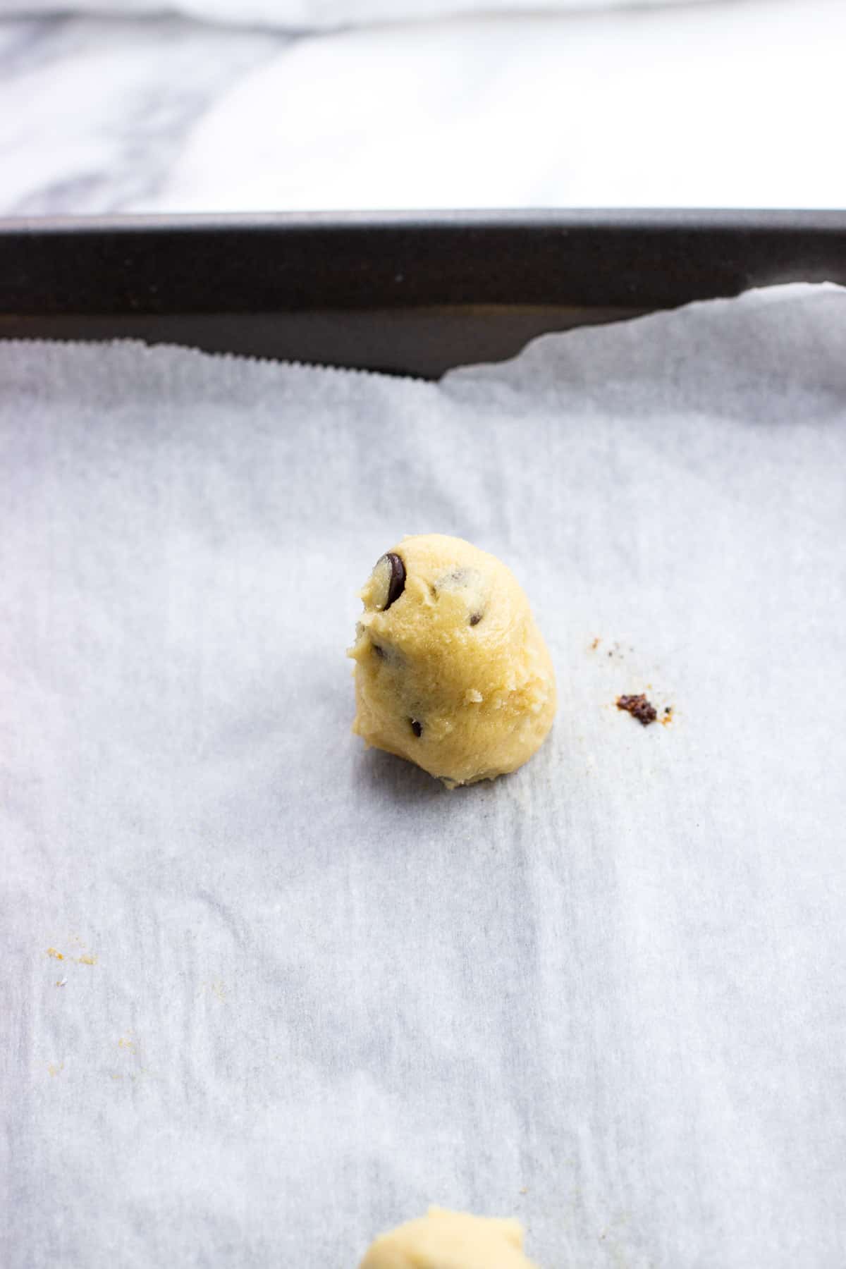 Tall oval shaped cookie dough on a parchment-lined sheet pan.