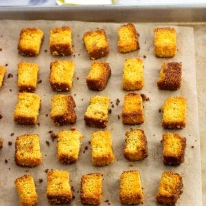 Baked cornbread croutons on a sheet pan.