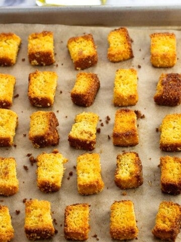 Baked cornbread croutons on a sheet pan.