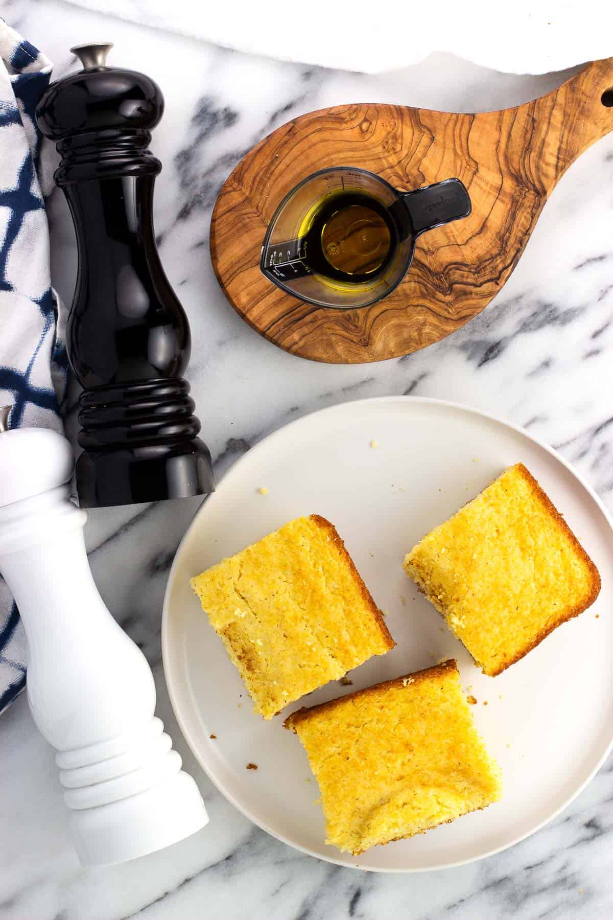 Squares of cornbread, olive oil, and salt and pepper mills.